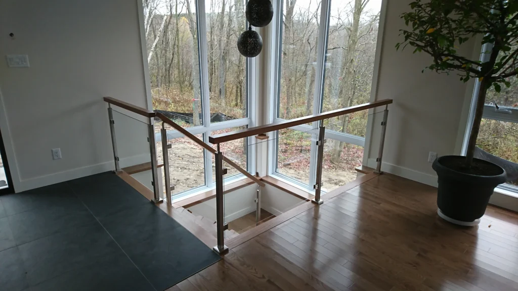 Escalier tournant à garde-corps de verre devant baies vitrées