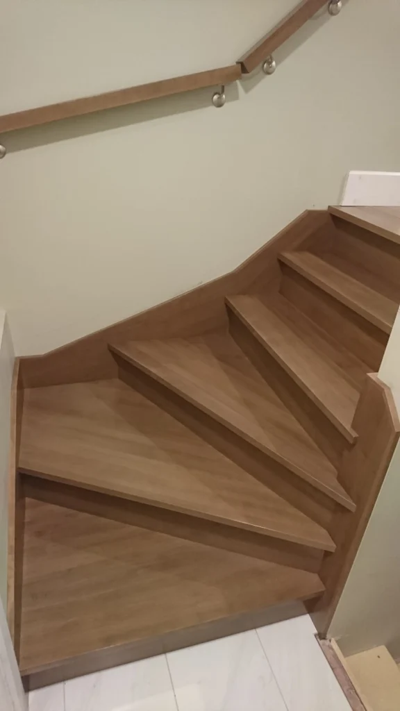 Escalier tournant en bois franc avec garde-corps de verre et poteaux métalliques — vue 1
