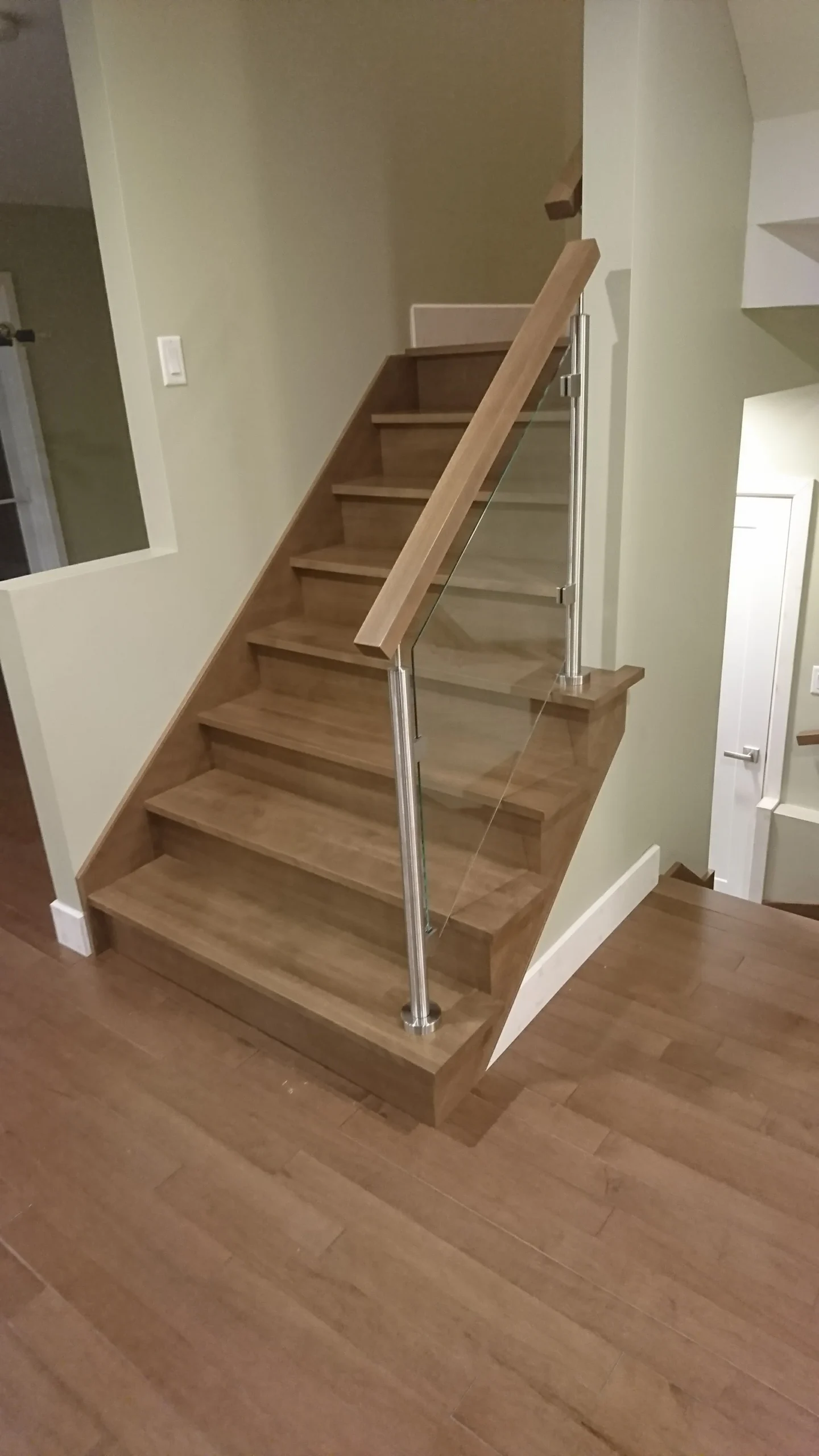 Escalier tournant en bois franc à garde-corps de verre et poteaux métalliques — vue principale