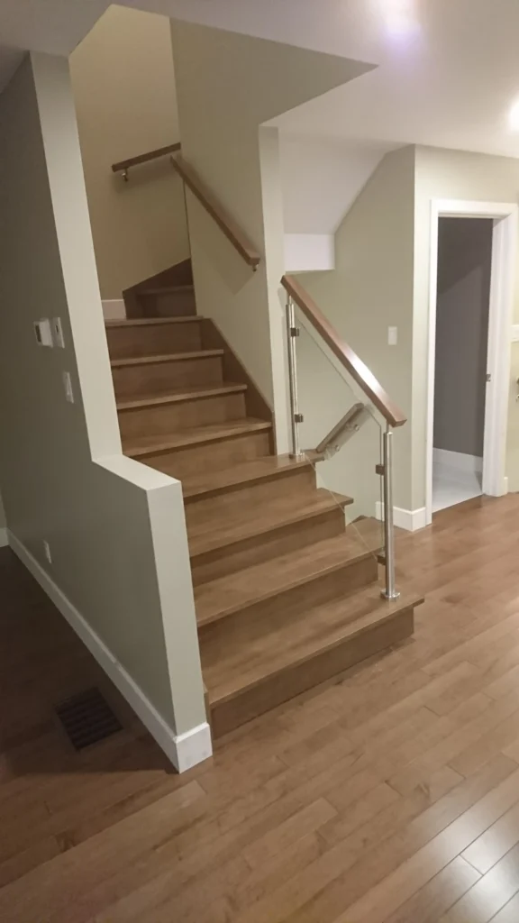 Escalier tournant en bois franc avec garde-corps de verre et poteaux métalliques — vue 4