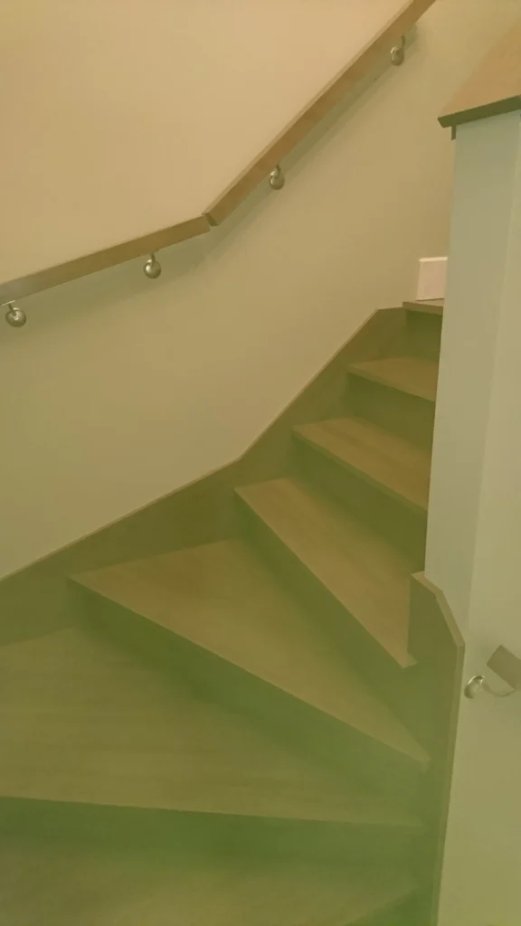 Escalier tournant en bois franc avec garde-corps de verre et poteaux métalliques — vue 5