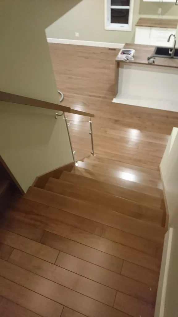 Escalier tournant en bois franc avec garde-corps de verre et poteaux métalliques — vue 7