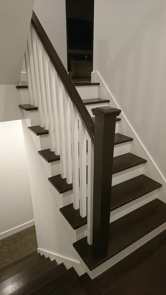 Escalier tournant bicolore en bois foncé et barreaux blancs