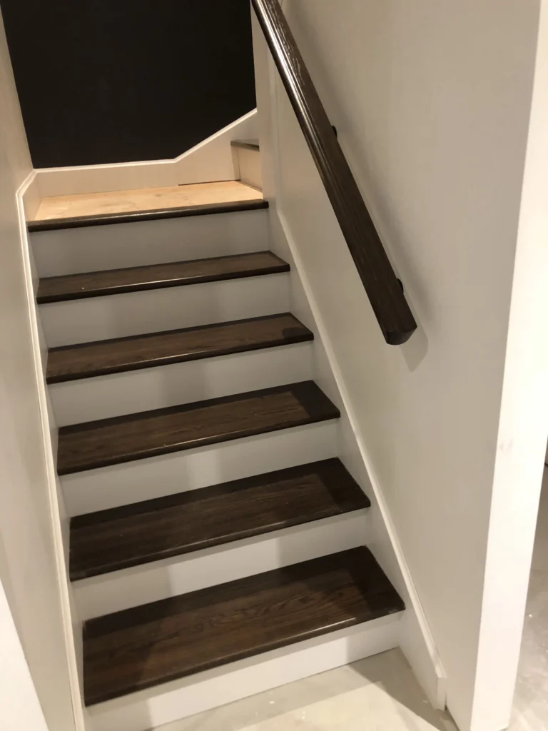 Escalier tournant en bois foncé avec barreaux de fer forgé — vue 1