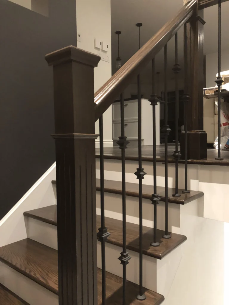 Escalier tournant en bois foncé à barreaux de fer forgé