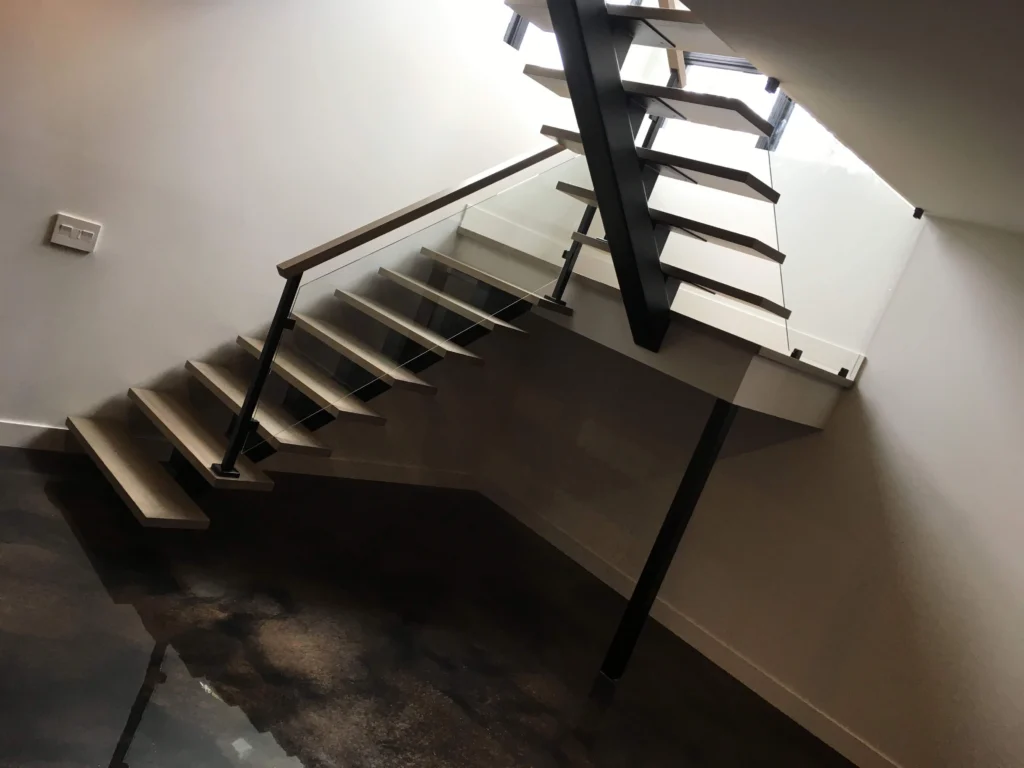 Escalier suspendu à contremarches ouvertes avec limons d'acier et garde-corps de verre — vue 1