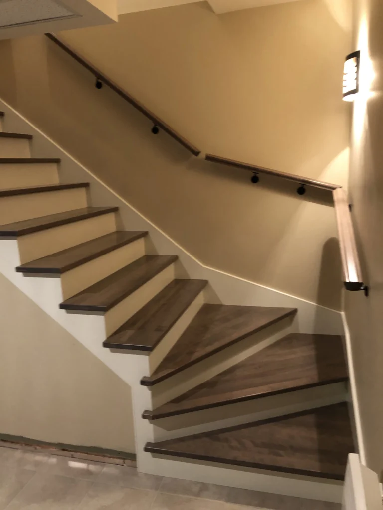 Escalier tournant en bois gris-brun à main courante murale