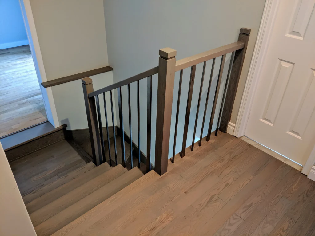 Escalier tournant en bois teinté gris à barreaux de métal noir