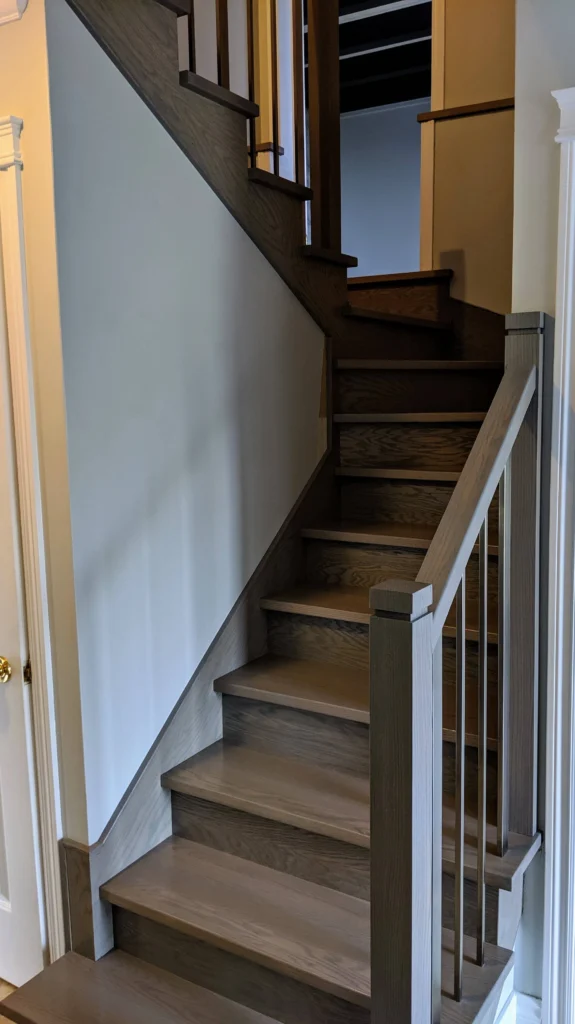 Escalier tournant en bois teinté gris-brun à barreaux carrés