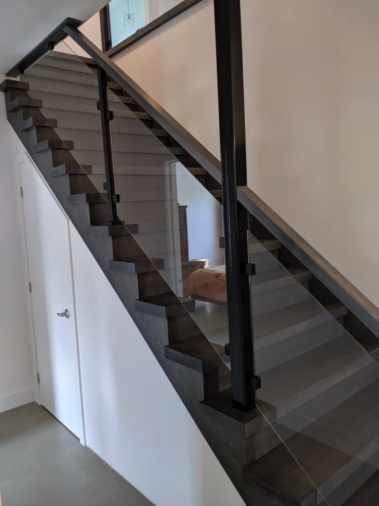 Escalier tournant gris-brun à garde-corps de verre et structure d&rsquo;acier