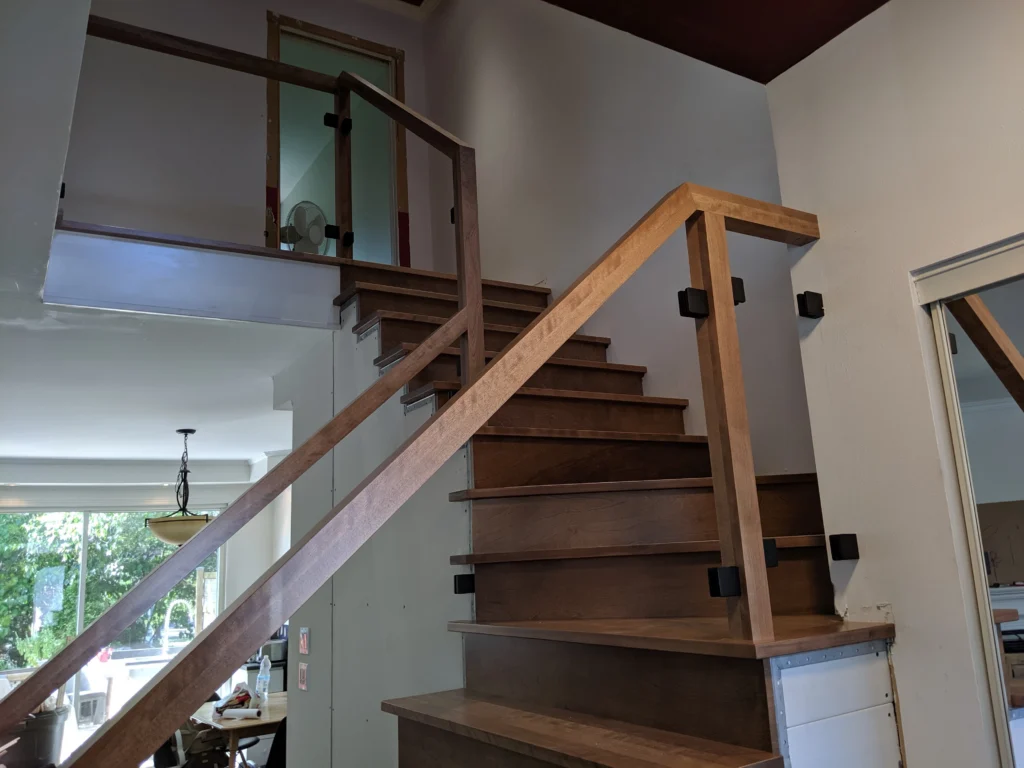 Escalier tournant de bois franc au ton miel et garde-corps de verre à Boucherville (vue 2)