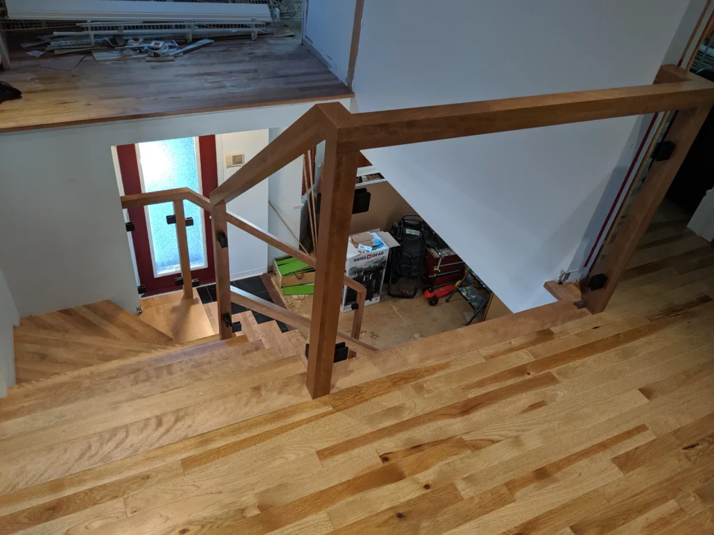Escalier tournant de bois franc au ton miel et garde-corps de verre