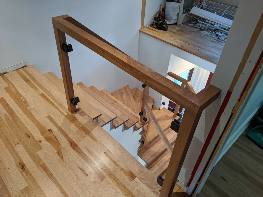 Escalier tournant de bois franc au ton miel et garde-corps de verre à Boucherville (vue 6)