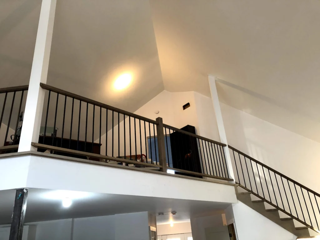 Escalier tournant de bois blond-gris à barreaux de métal noir à Chambly