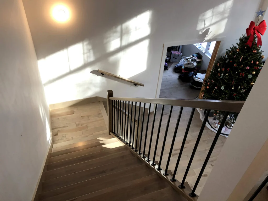 Escalier tournant de bois blond-gris à barreaux de métal noir