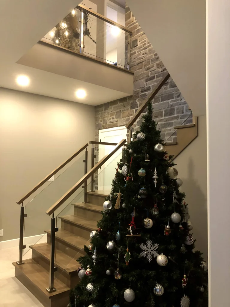 Escalier tournant de bois gris-brun à garde-corps de verre et poteaux de bois