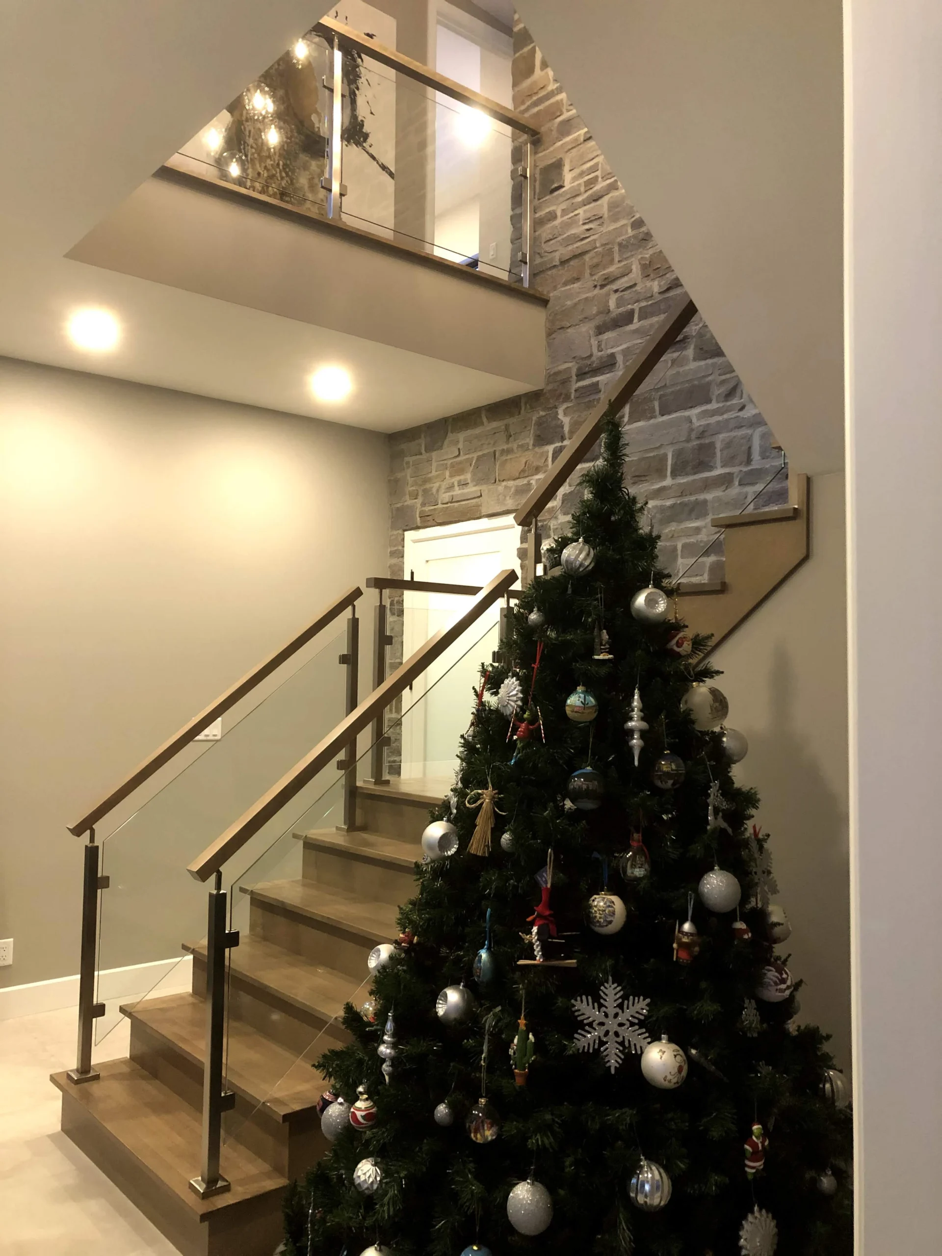 Escalier tournant de bois gris-brun à garde-corps de verre et poteaux de bois — vue principale