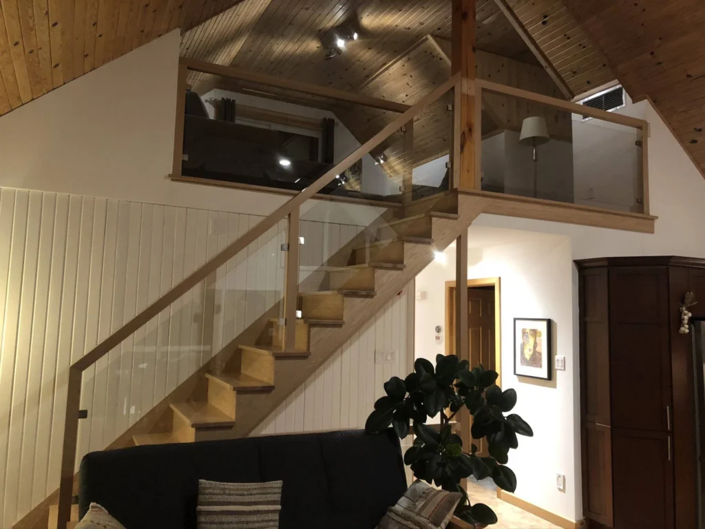 Escalier droit de bois clair à garde-corps de verre vers une mezzanine à Sherbrooke (vue 2)