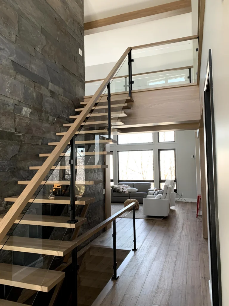 Escalier suspendu à marches de bois clair et garde-corps de verre