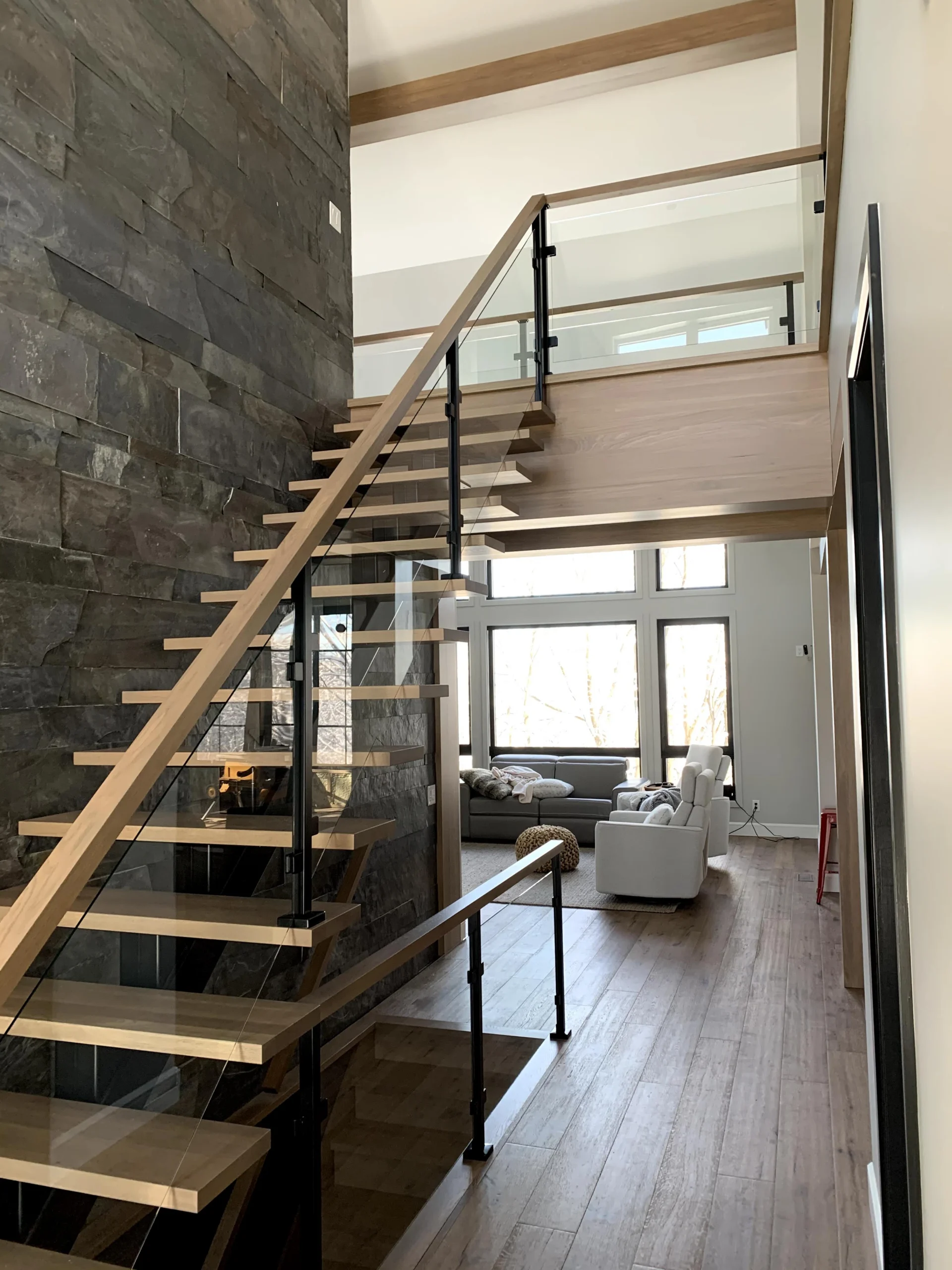 Escalier suspendu à marches de bois clair et garde-corps de verre — vue principale