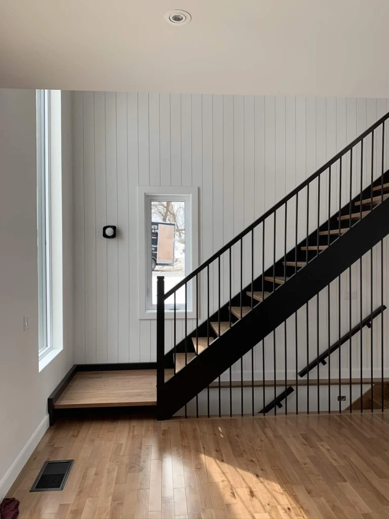 Escalier tournant de bois franc blond à garde-corps de métal noir à Granby
