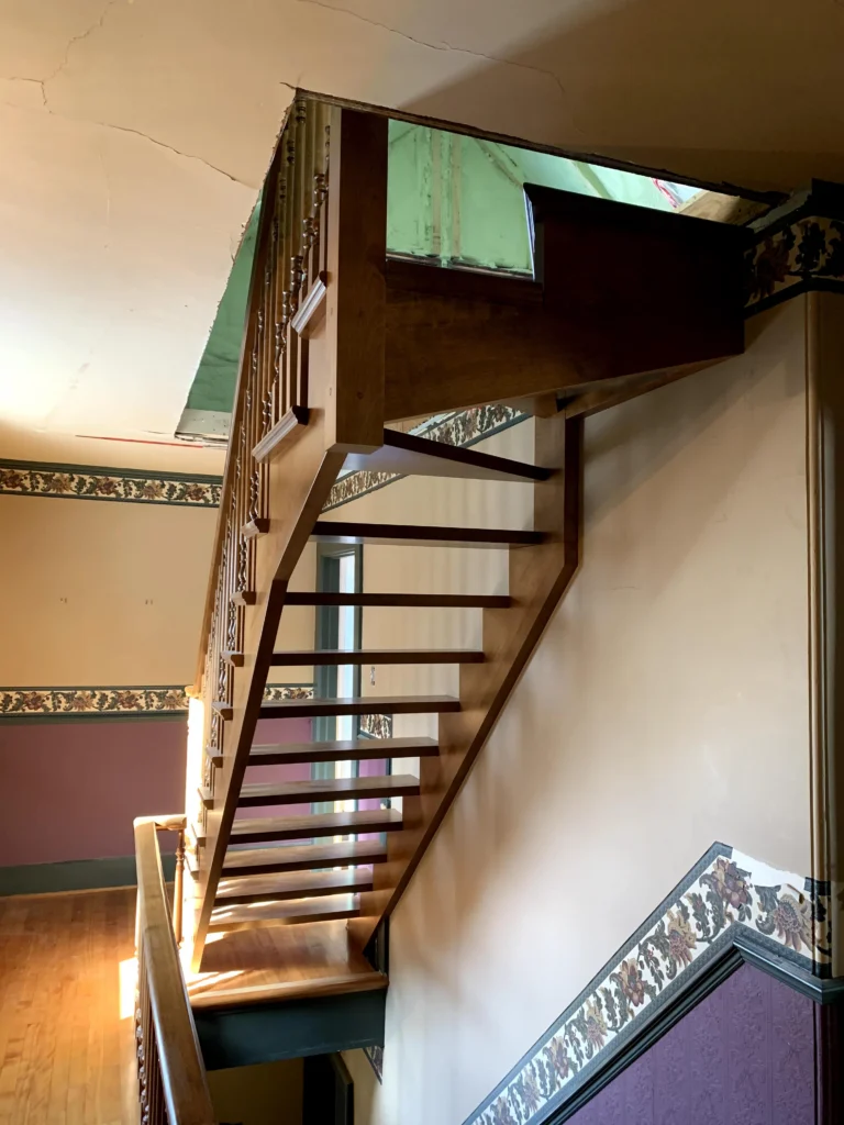 Escalier tournant de bois franc à barreaux tournés et contremarches ouvertes