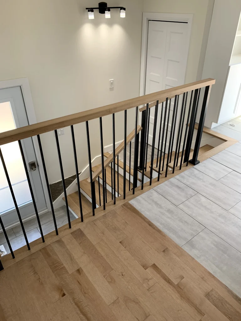 Escalier tournant d'érable à barreaux de métal noir et main courante d'érable à Boucherville (vue 2)
