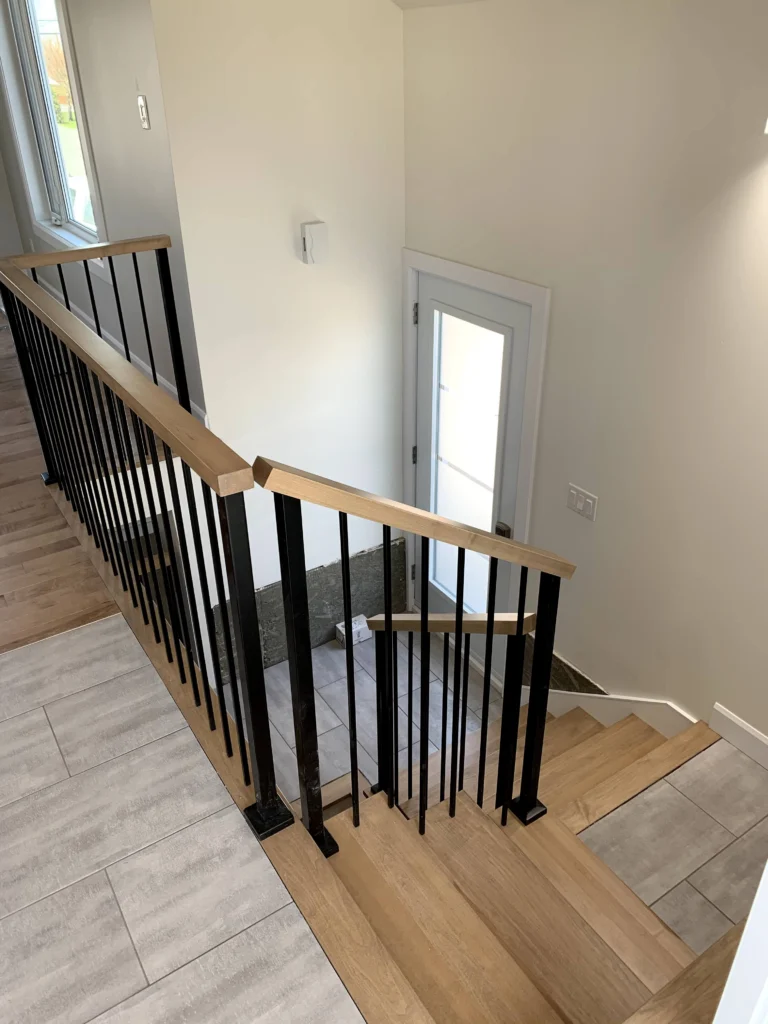 Escalier tournant d'érable à barreaux de métal noir et main courante d'érable à Boucherville (vue 3)