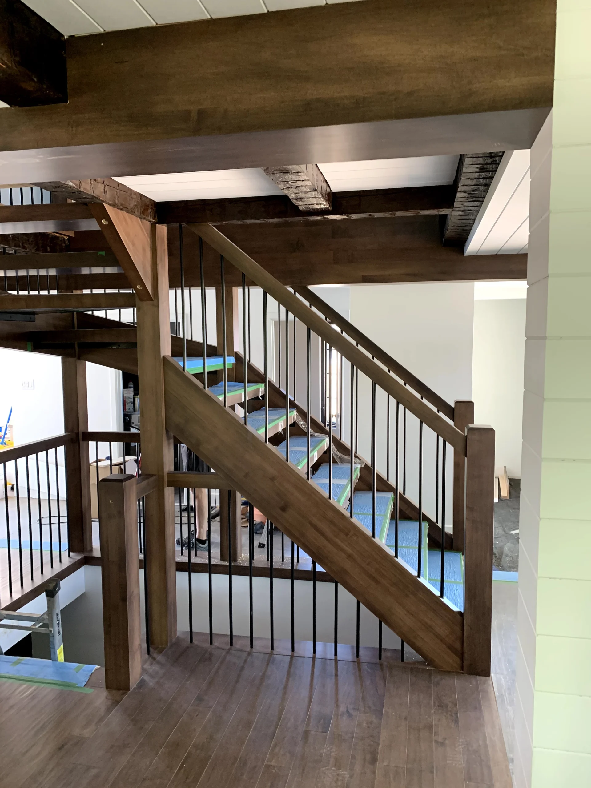 Escalier tournant de bois foncé à barreaux de métal noir et poutres apparentes — vue principale