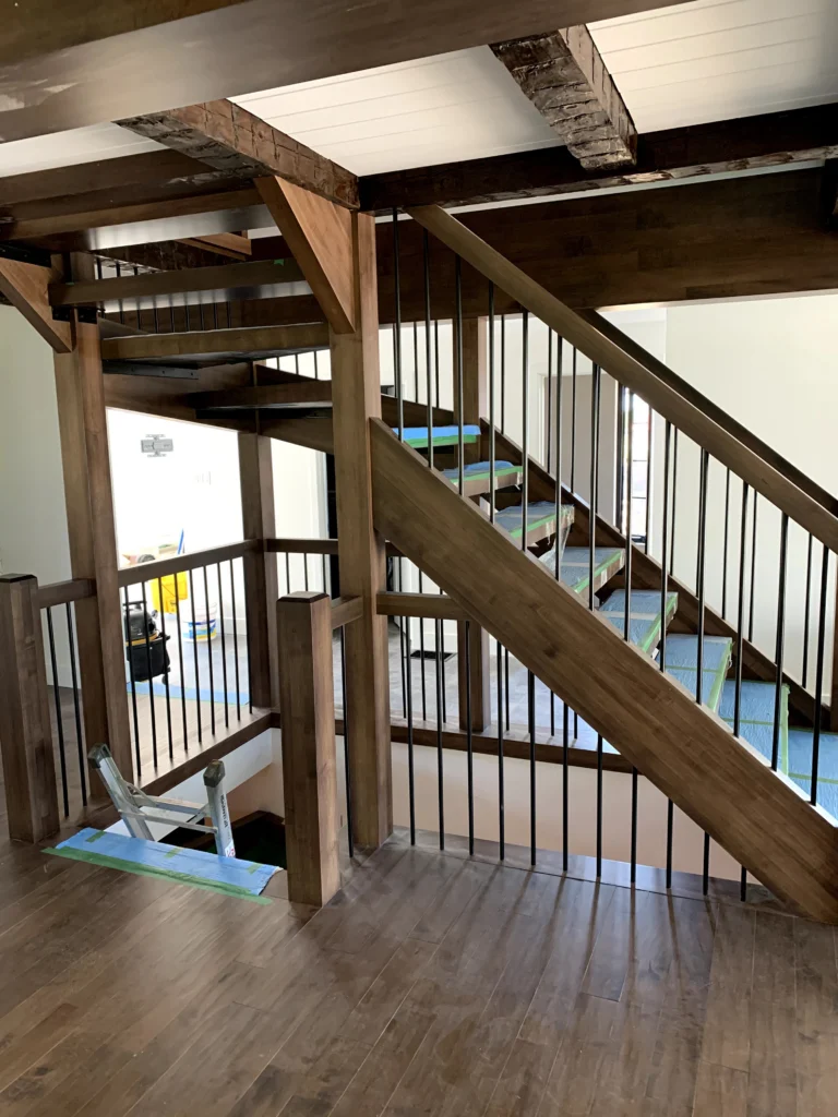 Escalier droit en bois teinté noyer à barreaux métalliques et poutres apparentes