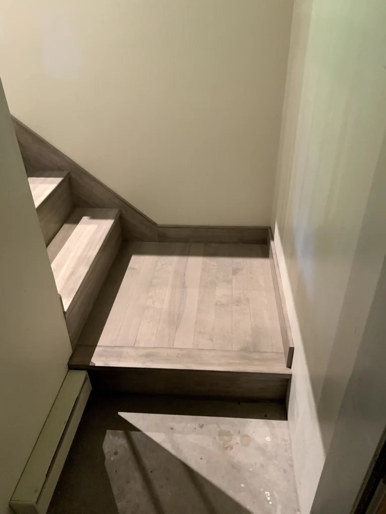 Palier d'escalier en bois blanchi gris entre deux murs clairs