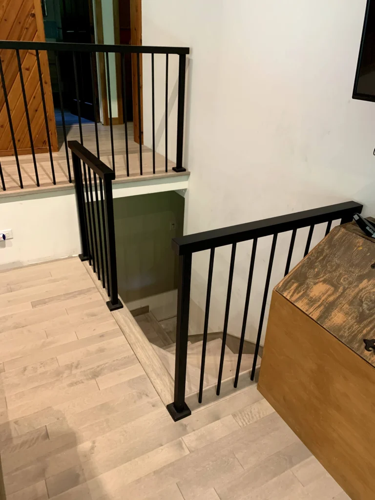Escalier tournant en bois blanchi gris et garde-corps de métal noir