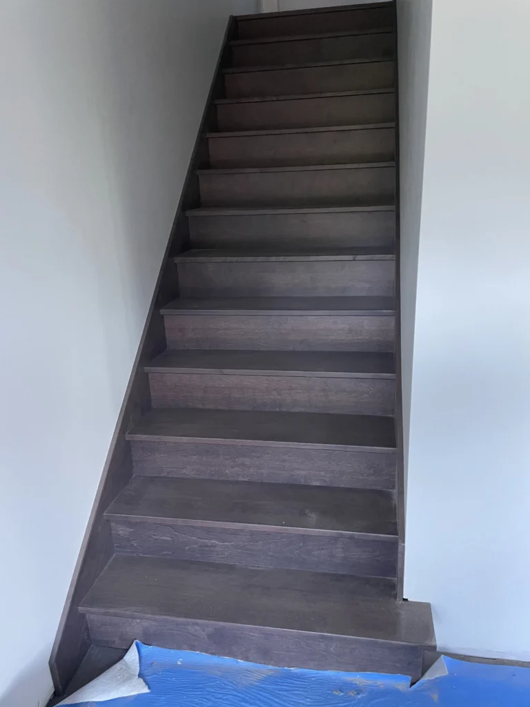 Escalier droit en bois teinté gris-brun entre murs