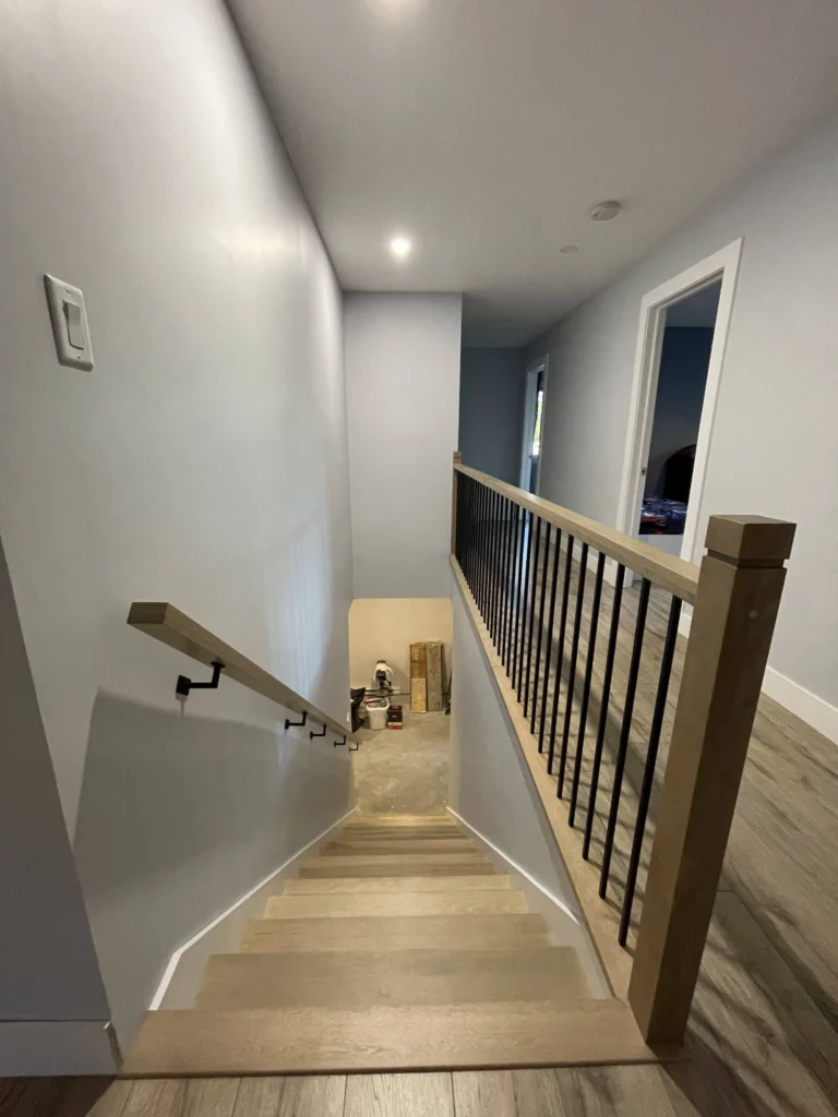 Vue plongeante sur un escalier droit en bois clair éclairé par un ruban DEL