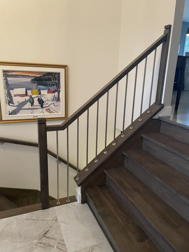 Escalier tournant en bois teinté foncé à barreaux métalliques dans un hall
