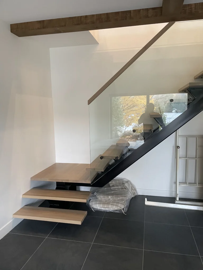 Escalier suspendu en chêne blanc sur limon central d'acier noir avec garde-corps de verre