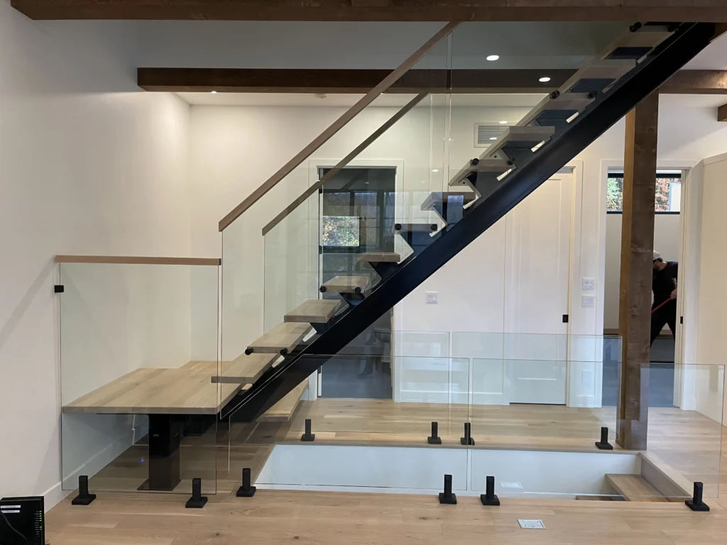 Escalier moderne en chêne blanc avec limon d'acier noir et vue sur le séjour