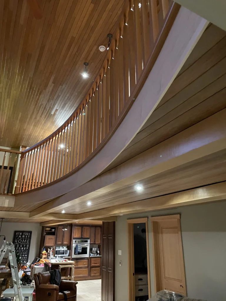 Galerie de mezzanine courbe en bois miel avec barreaux de bois sous un plafond de bois