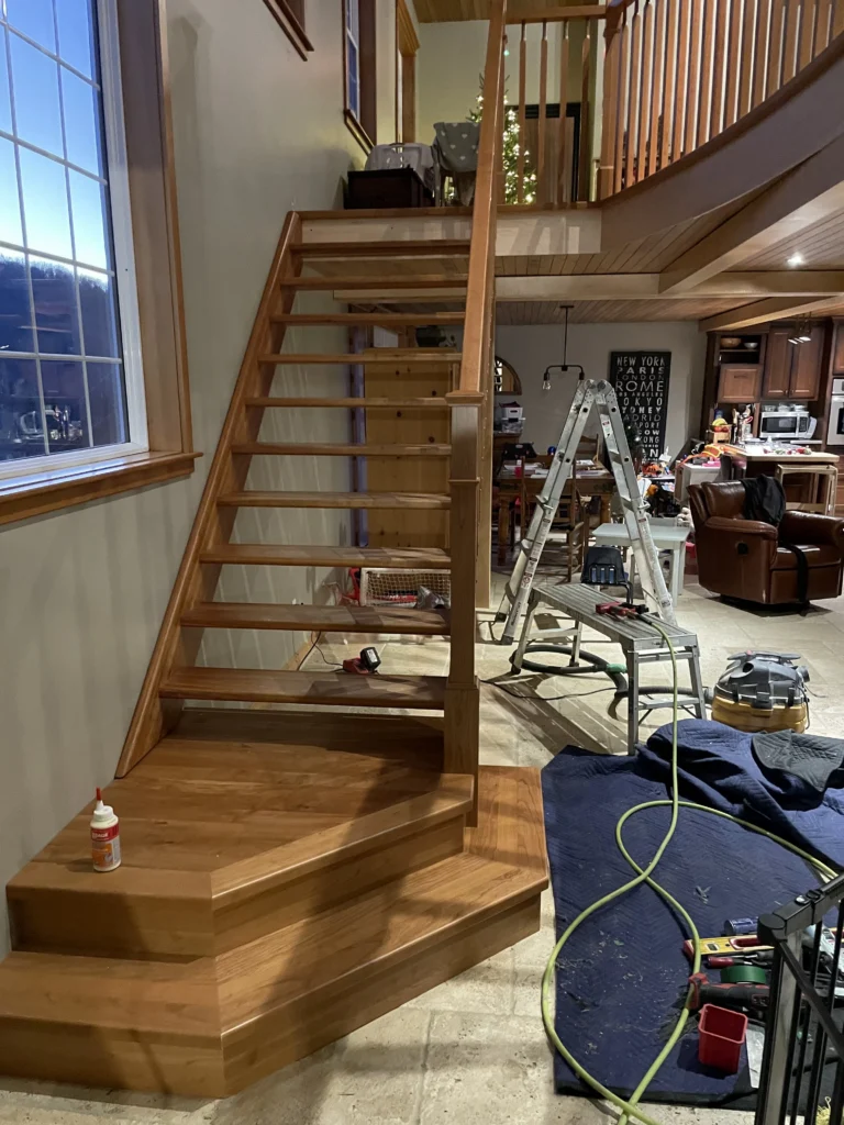 Escalier droit à contremarches ouvertes menant à une galerie courbe en bois