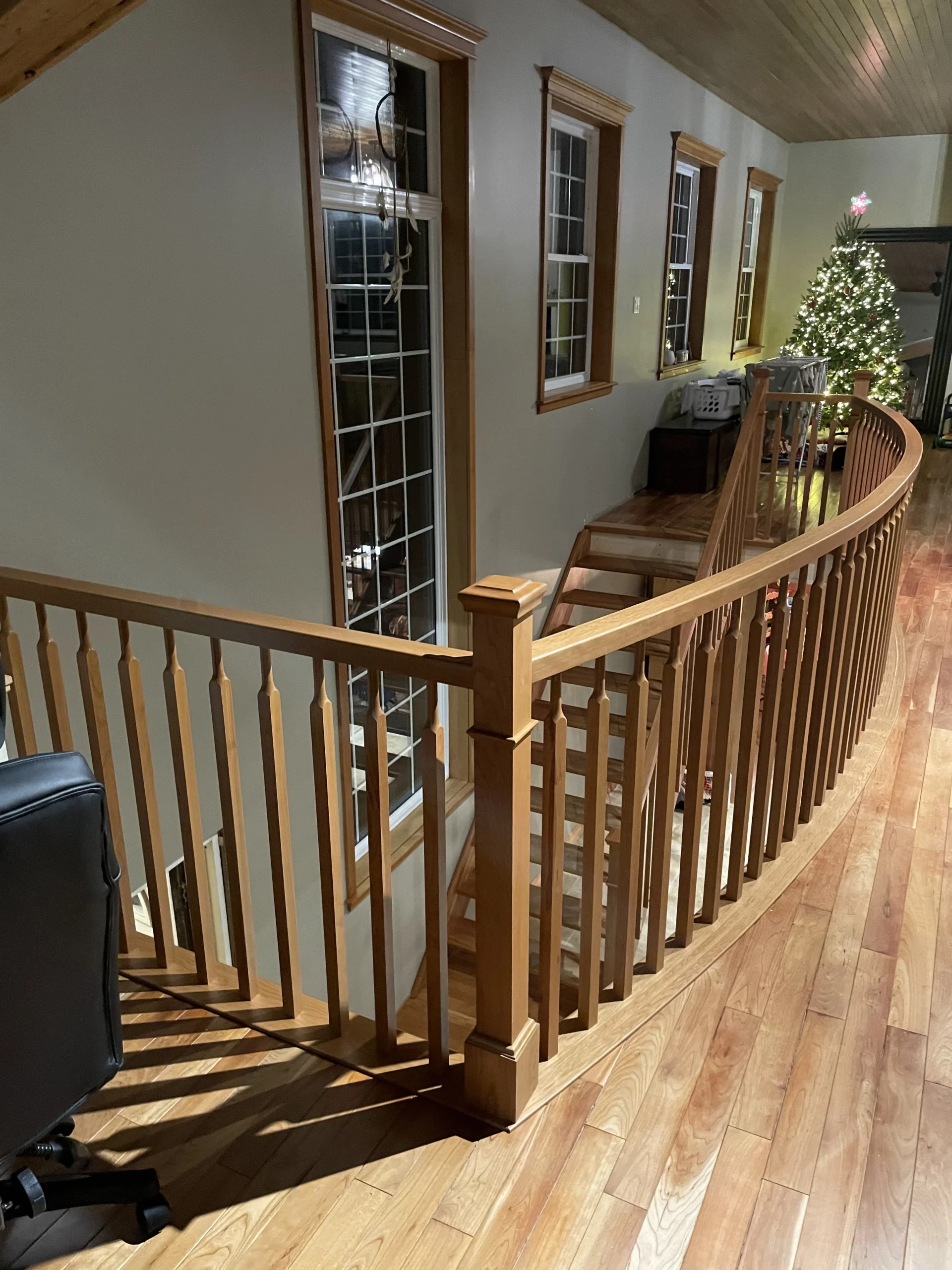 Galerie de mezzanine courbe à barreaux de bois au-dessus d&rsquo;un escalier — vue principale