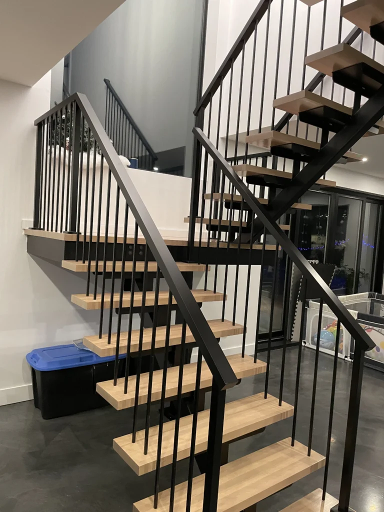 Escalier à deux volées sur limon central d'acier avec garde-corps de métal noir