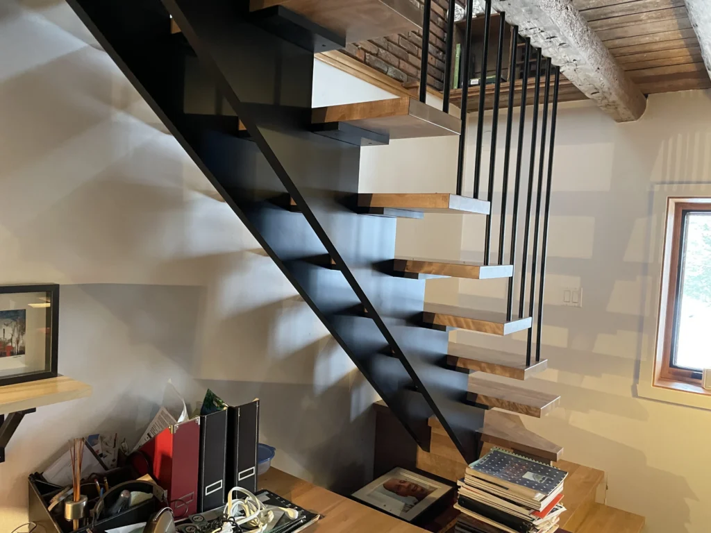 Détail des tiges verticales de métal noir et des marches de chêne d'un escalier suspendu
