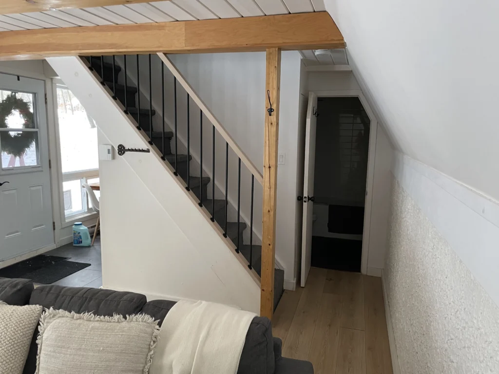 Rampe de l'escalier vue depuis le salon, bois clair et métal noir