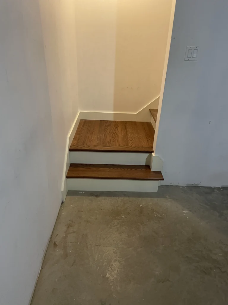 Bas de l'escalier en bois teinté noyer et contremarches blanches à Saint-Lambert