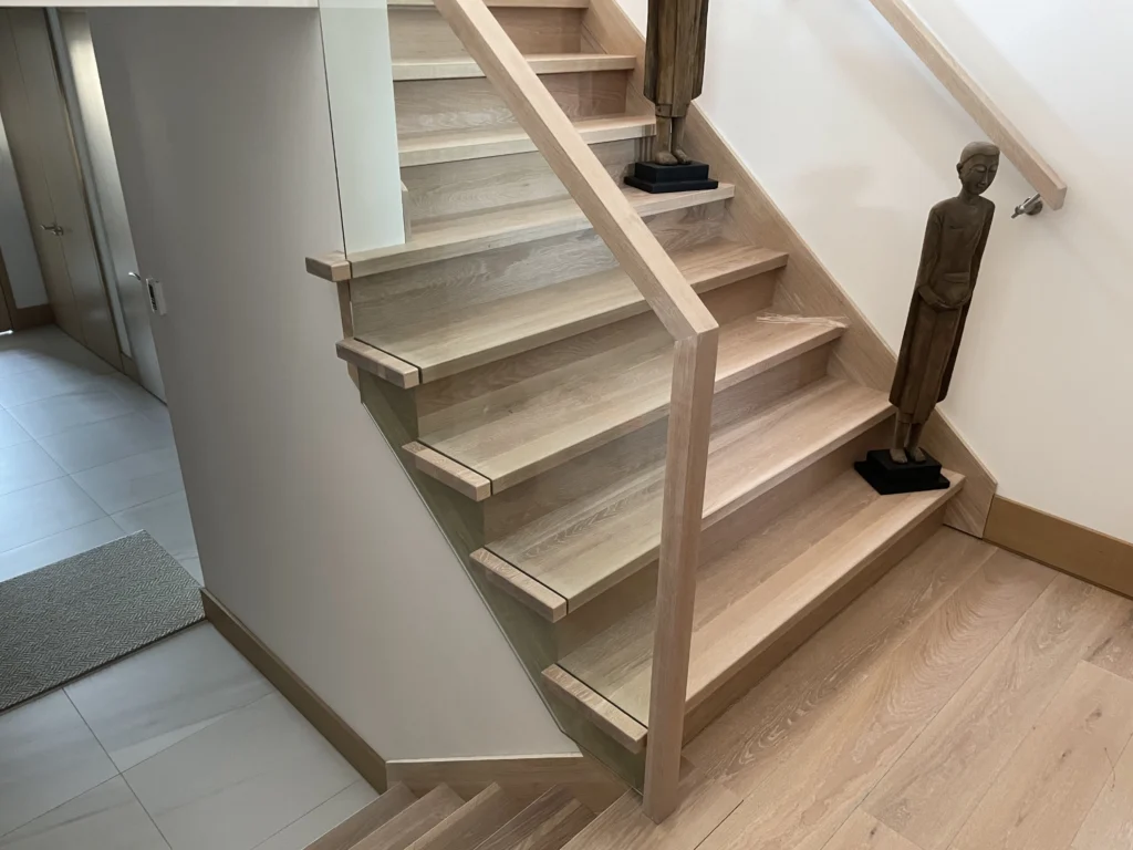 Escalier de chêne blanchi et garde-corps de verre dans une grange rénovée