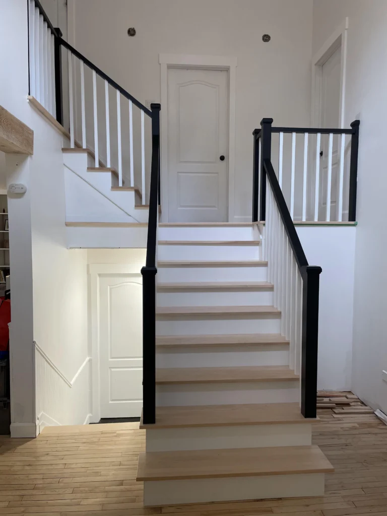 Escalier tournant à barreaux de bois tournés et poteaux noirs