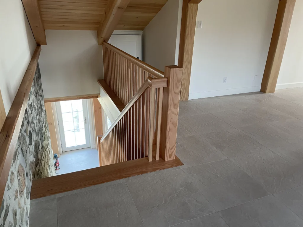 Palier de mezzanine et escalier de bois clair descendant vers l'entrée