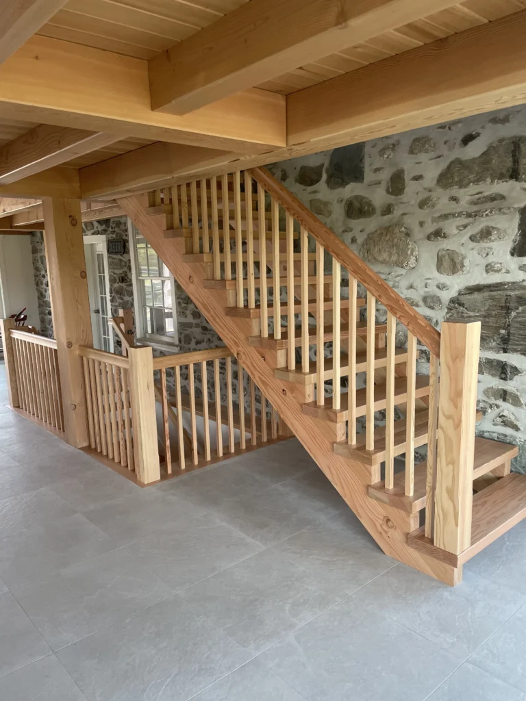Escalier de bois clair et mezzanine à barreaux dans une maison de pierre