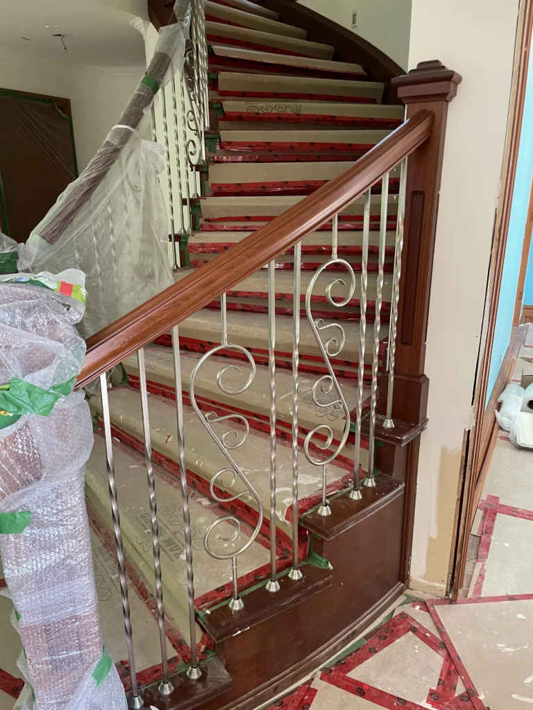 Escalier tournant teinté acajou à balustrade de fer forgé