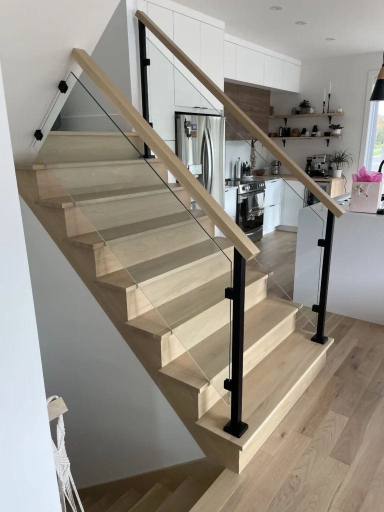 Escalier tournant en chêne blanc avec garde-corps de verre et poteaux noirs